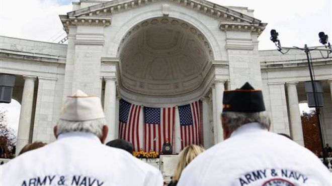 Two veterans listen to President Obama during a Veterans Day address. A Department of veterans Affairs Inspector-General report says VA officials have fixed a computer glitch that delayed claims processing but VA employees aren't properly using the remedy. AP Photo