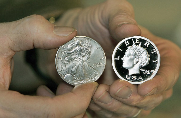 FILE PHOTO - U.S. Mint Silver Dollar, left, and a Liberty Dollar Coin, right. (AP Photo/Alan Marler)
