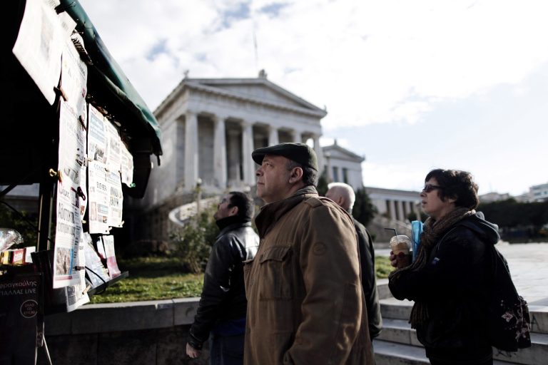   Pedestrians read Greek newspapers posted in front of the Academy building in central Athens, on Wednesday, Dec. 12, 2012. Greece will buy back Euro 31.9 billion ($41.5 billion) of its bonds from private investors at a third of their nominal price, the debt management agency said Wednesday, lightening its crushing debt load and meeting a key condition to receive vital rescue loans.(AP Photo/Petros Giannakouris)  