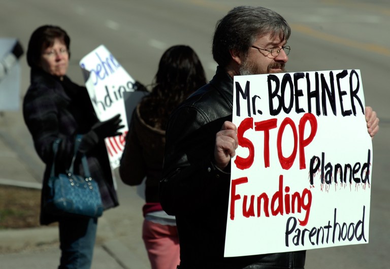   FILE - In this Monday, March 7, 2011 file photo, Dave Smith, right, from Clear Mountain Church in Williamsburg, Ohio, protests the federal funding of Planned Parenthood in front of John Boehner's district office in West Chester Township, Butler County, Ohio. Ohio Senate president Tom Niehaus spiked a trio of controversial bills less than a month after Democratic President Barack Obama won the state for the second time. The bills Niehaus blocked would have severely limited abortion, jeopardized Planned Parenthood funding and tightened voter ID rules. (AP Photo/Middeltown Journal, Gary Stelzer, File)  