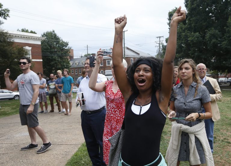 Charlottesville resident, Aaliyah Jones, cheers as city workers drape a tarp over the statue of Confederate General Robert E. Lee in Emancipation park in Cahrlottesville, Va., Wednesday, Aug. 23, 2017. (AP Photo/Steve Helber)