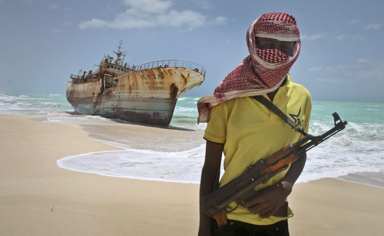 FILE - In this Sunday, Sept. 23, 2012 file photo, masked Somali pirate Hassan stands near a Taiwanese fishing vessel that washed up on shore after the pirates were paid a ransom and released the crew, in the once-bustling pirate den of Hobyo, Somalia. Three Somali pirates were killed in a fight over the ransom paid to free the German-American journalist Michael Scott Moore who was released this week after two years and eight months of captivity, a Somali police official said Friday, Sept. 26, 2014. (AP Photo/Farah Abdi Warsameh, File)