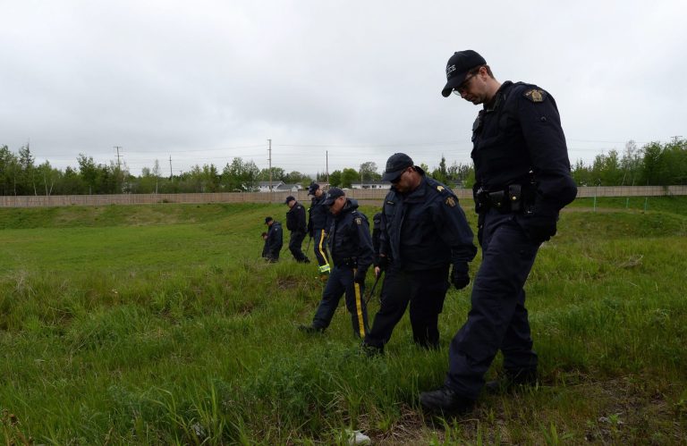 RCMP officers scour a field in Moncton, N.B. on Saturday, June 7, 2014 not far from where officers arrested a man charged with killing three of their colleagues.  A few dozen Mounties are searching for clues behind the residential area where suspected gunman Justin Bourque was apprehended Friday. Bourque is facing three charges of first-degree murder and two counts of attempted murder in the shootings of five RCMP officers.  (AP Photo/The Canadian Press, Sean Kilpatrick)