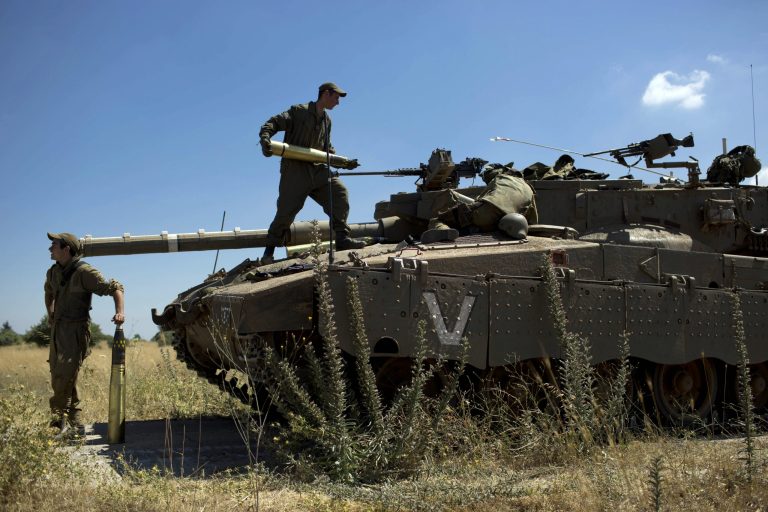 Israeli soldiers load shells in their tank following the first death on the Israeli side of the Golan since the Syrian civil war erupted more than three years ago, near the Israeli village of Alonei Habashan, in the area of Tel Hazeka, close to the Quneitra border crossing in the Israeli-controlled Golan Heights, Sunday, June 22, 2014. A civilian vehicle in the Golan Heights was targeted by forces in neighboring Syria on Sunday in an attack that killed a 15-year-old boy and prompted Israeli tanks to retaliate by firing on Syrian government targets, the Israeli military said. (AP Photo/Oded Balilty)