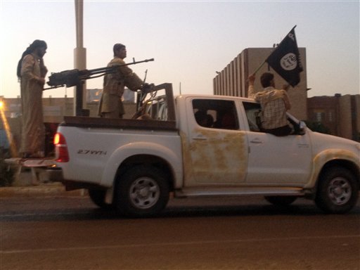In this file photo taken Monday, June 23, 2014, Islamic State fighters, parade in a commandeered Iraqi security forces vehicle on a main road at the northern city of Mosul, Iraq. (AP Photo, File)
