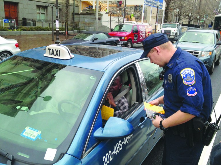Alan Blinder/For the Examiner
A District police officer distributes a flier about the city's toughened U-turn law to a taxi driver on Pennsylvania Avenue on Wednesday.