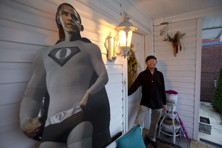   In this Thursday, Dec. 20, 2012, photo, Bernard Duval, innkeeper of the Aunt Bee's Little White House B&B, stands in the doorway by a cutout of President Barack Obama in a super hero outfit, at the B&B in Washington. The six-room bed and breakfast in northeast Washington still had two rooms available for the presidential inauguration as of the week before Christmas, with rates starting at $225 a night. (AP Photo/Jacquelyn Martin)  