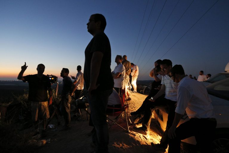 Israelis stand on a hill at the Israeli town of Sderot, overlooking the Gaza Strip, as they wait to watch Israeli forces' bombardment and missiles fired by Palestinian militants from inside Gaza towards Israel, Thursday. (AP/Lefteris Pitarakis)