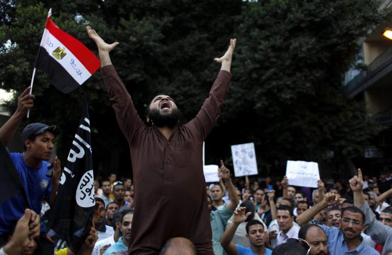 FILE - In this Wednesday, Sept. 12, 2012 file photo, Egyptian protesters carry their national flag and a flag with Arabic that reads 