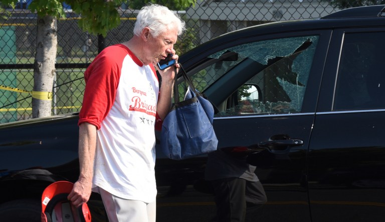 Rep. Jack Bergman, R-Mich. talks on the phone while walking past a car with a broken window near the baseball field in Alexandria, Va., Wednesday, June 14, 2017, where a gunman fired on Republican members of Congress practicing for a game. (AP Photo/Kevin S. Vineys)
