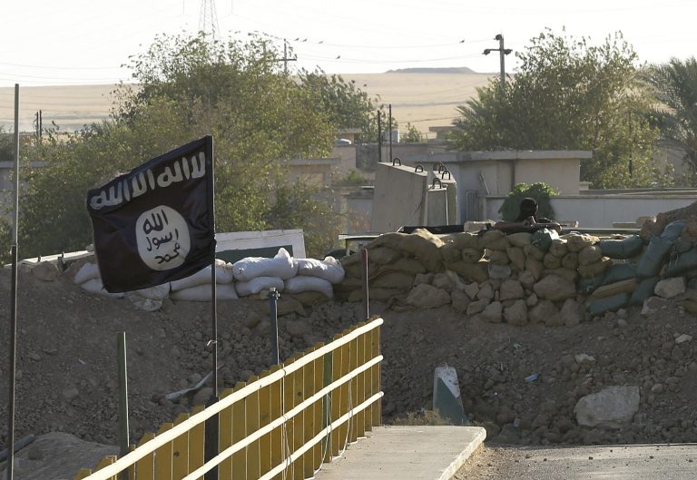 A black flag used by the Islamic State group flutters over their combat positions on the front line with Kurdish Peshmerga fighters at the Mullah Abdullah Bridge, located between Irbil and Kirkuk, 290 kilometers (180 miles) north of Baghdad, Iraq, Saturday, Sept. 27, 2014. (AP Photo/Hadi Mizban)