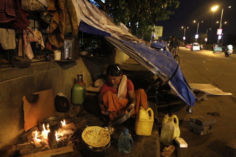 An Indian woman prepares food outside her makeshift dwelling on a pavement in Ahmadabad, India, Friday, July 3, 2015. (AP Photo/Ajit Solanki)