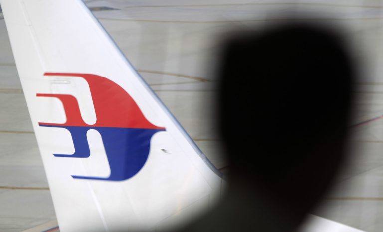 FILE - In this Sunday, March 9, 2014, file photo, a man looks out from a viewing gallery as a Malaysia Airlines aircraft sits on the tarmac at Kuala Lumpur International Airport in Sepang, Malaysia. With the search for the missing Malaysia Airlines Flight 370 entering its eighth day, scenarios involving piracy or hijacking are increasingly being talked about as possible explanations for the disappearance of the Boeing 777 with 239 people on board. (AP Photo/Lai Seng Sin, File)