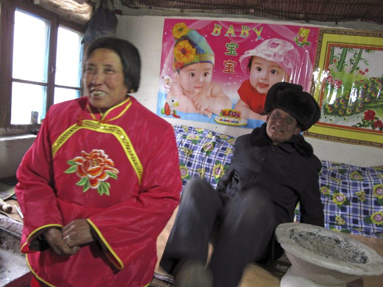 In this photo taken Monday, Feb. 25, 2013, corn farmer Tang Rongbin, right, and his wife Gu Baoqing smile inside Tang's home in Luotuowan village in northern China's Hebei province. Chinese leader Xi Jinping visited Tang in December 2012 as part of efforts to style himself as a no-frills man-of-the-people. Xi has also presented himself as an economic reformer and an iron-fisted graft-buster, spurring expectations for change, but as he prepares to be appointed president, pressure will be growing on him to deliver. (AP Photo/Gillian Wong)