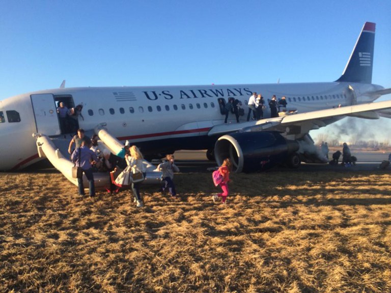 Passengers evacuate US Airways Flight 1702 after the pilot was forced to abort takeoff shortly after 6 p.m., after a tire on the plane's front landing gear blew out, Thursday, March 13, 2014, in Philadelphia. The Airbus A320 jet, bound for Fort Lauderdale, Fla., was carrying 149 passengers and five crew members, airport spokeswoman Victoria Lupica said. All were rescheduled on departing flights Thursday night, she said. (AP Photo/Dennis Fee)
