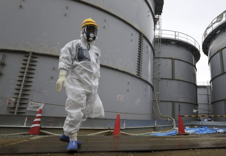 A Tokyo Electric Power Co. employee wearing a protective suit and a mask walks past storage tanks for radioactive water in the H4 area at the Fukushima Dai-ichi nuclear power plant in Okuma, Fukushima, northeastern Japan, Thursday, Nov. 7, 2013.  The plant has recently had a series of mishaps, including leaks of radioactive water from storage tanks. The incidents, many of them caused by human error, have added to concerns about TEPCO's ability to safely close down the plant, which suffered multiple meltdowns after being hit by a March 2011 earthquake and tsunami. (AP Photo/Tomohiro Ohsumi, Pool)