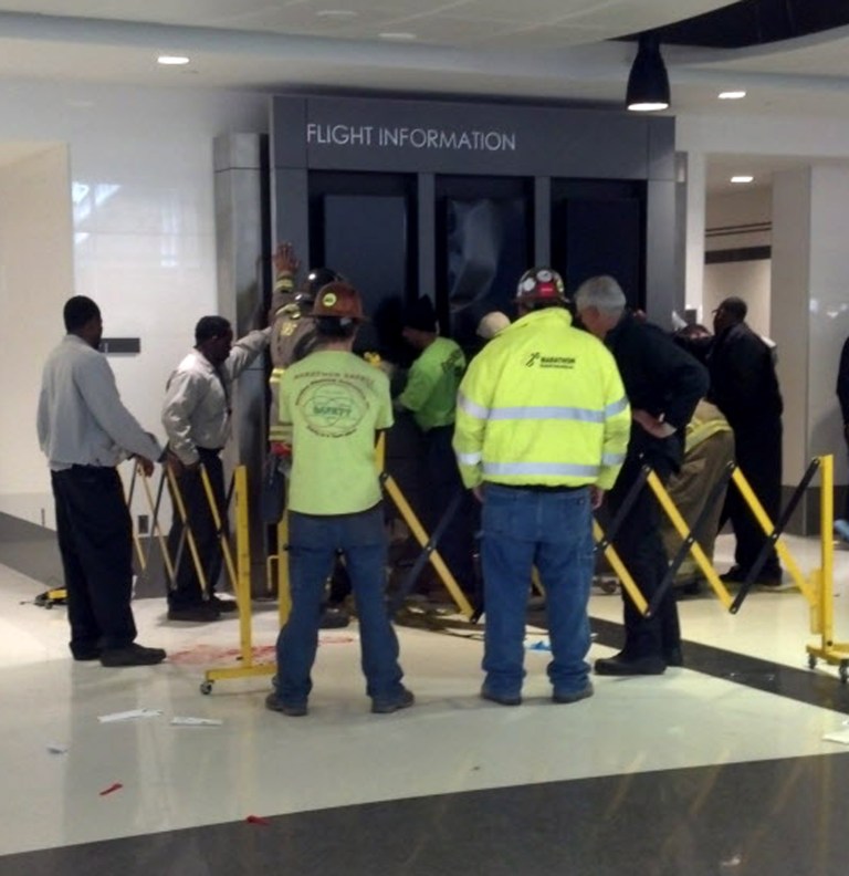 People hold up a message board sign that fell on a family killing a child and injuring the mother and two other children in the terminal at the Birmingham-Shuttlesworth International Airport in Birmingham, Ala., Friday, March 22, 2013. (AP Photo/ AL.com, Carol Robinson) MAGS OUT