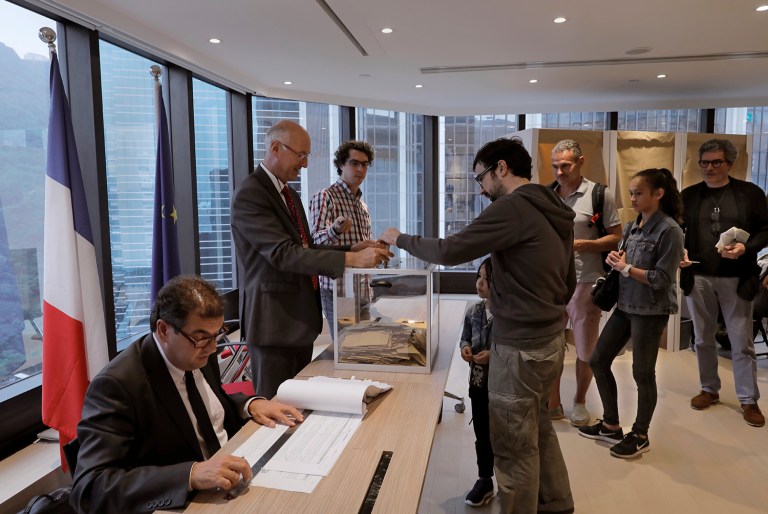 French people line up before casting their votes for the first-round presidential election at a polling station at the consulate general of France in Hong Kong, Sunday, April 23, 2017. (AP Photo/Vincent Yu)