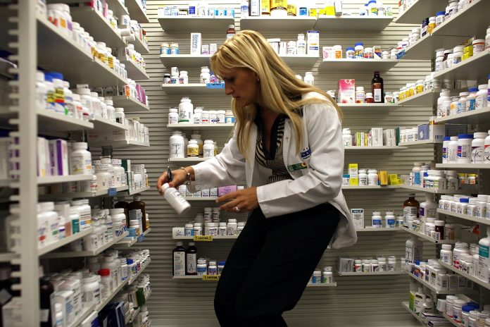 Roxana Selagea, a Publix supermarket pharmacy manager, retrieves a bottle of antibiotics from the shelf.