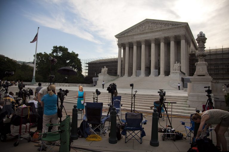 Journalist wait outside the Supreme Court awaiting decisions in unresolved major cases.  The Supreme Court on Monday issued an opinion that struck down parts of Arizona's immigration law but upheld its most controversial component.  (AP Photo/Evan Vucci)