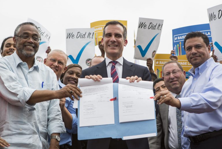 L.A. Mayor Eric Garcetti, center, stands with council members after signing into law an ordinance that will gradually raise the minimum wage to $15 an hour by 2020. (AP Photo/Ringo H.W. Chiu)