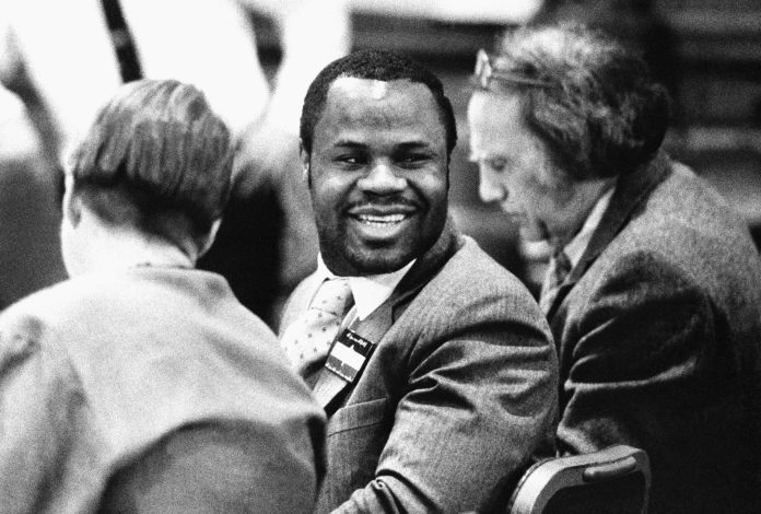 Larry Davis, known as "Loco Larry" on the streets of the Bronx, had racked up a mile-long rap sheet by age 20. Davis, center, flashes a smile as his lawyer, William Kunstler, right, sits beside him during Davis' trail in New York at the Bronx County courthouse, on Nov. 18, 1988. Davis is charges with attempted murder during a shootout with nine police officers in 1986. (AP Photo/pool)