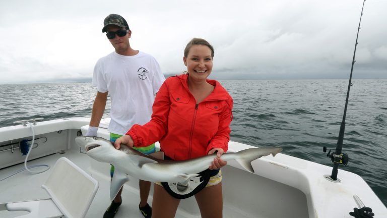 ADVANCED FOR RELEASE SUNDAY, AUGUST 17, 2014 Rachel Hibberd holds an Atlantic sharpnosed shark she caught on the Git-R-Done off the coast of Virginia Beach on Tuesday, Aug. 5, 2014.  At left is mate Frank Riganto. (AP Photo/The Virginian-Pilot, Steve Earley)