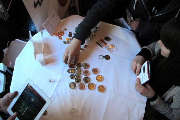 FILE - In this Feb. 12, 2014 file photo, attendees of the Inside Bitcoins conference in Berlin examine Bitcoin buttons. The website of major Bitcoin exchange Mt. Gox is offline amid reports it suffered a debilitating theft of the virtual currency, and the URL of the Tokyo-based outfit returns a blank page on Tuesday, Feb. 25, 2014. (AP Photo/Frank Jordans, File)
