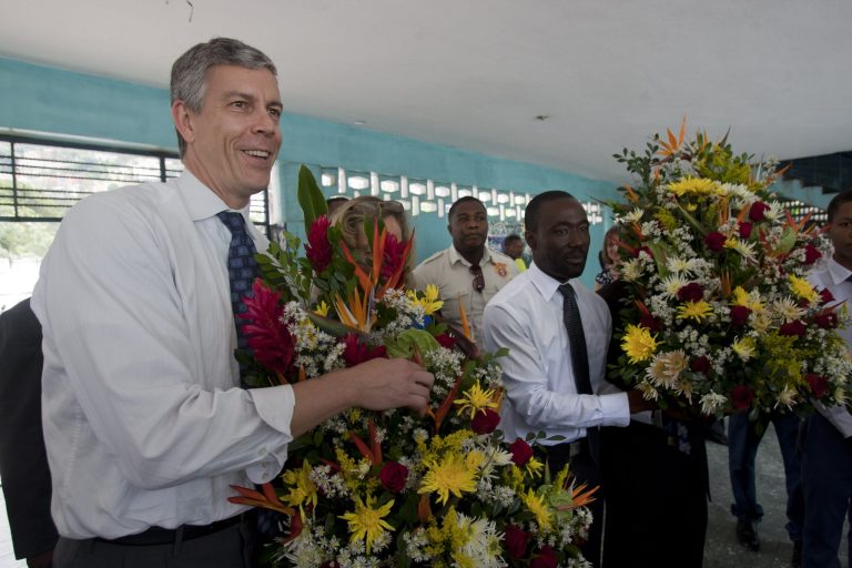 U.S. Secretary of Education Arne Duncan, left, stands with Haiti's Education Minister Vanneur Pierre holding flowers given to them by students at the Lycee de Petion-Ville school in Petion-Ville, Haiti, on Tuesday. (AP/Dieu Nalio Chery)