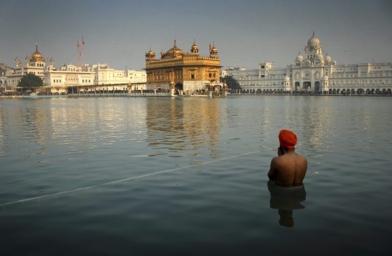 FILE- In this Jan. 1, 2014 file photograph, an Indian Sikh devotee takes a holy dip in the sacred pond at the Golden Temple in Amritsar, India. The British government has admitted it advised India before the deadly 1984 raid on the Golden Temple in Amritsar.Foreign Secretary William Hague told Parliament on Tuesday, Feb. 4, 2014 that British military advice had only a 