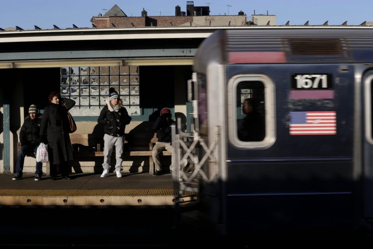   Commuters watch as a train enters the 40th St-Lowry St Station, where a man was killed after being pushed onto the subway tracks, in the Queens section of New York, Friday, Dec. 28, 2012. Police are searching for a woman suspected of pushing the man and released surveillance video Friday of her running away from the station.(AP Photo/Seth Wenig)  
