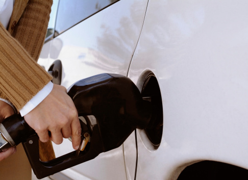 Woman putting gas in the tank of her car, extreme close-up