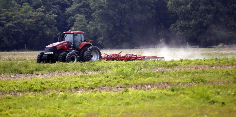 In this July 30, 2013 photograph, a farm tractor is seen tilling a field in Tunica, Miss. Area residents are hopeful at the promise of the jobs and tax base the opening of a GreenTech Automotive's Tunica assembly facility could provide in the Delta, where only farming, casinos and scant manufacturing jobs exist. (AP Photo/Rogelio V. Solis)