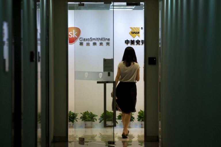FILE - In this July 11, 2013 file photo, a woman enters an office of GlaxoSimthKline in Beijing. Drug maker GlaxoSmithKline was fined $492 million on Friday, Sept. 19, 2014 for bribing doctors in China in the biggest such penalty ever imposed by a Chinese court. The court sentenced the company's former China manager, Briton Mark Reilly, and four Chinese co-defendants to prison but postponed the sentences for two to four years, suggesting they may never be served. The court said it granted leniency because the defendants confessed. (AP Photo/Alexander F. Yuan, File)