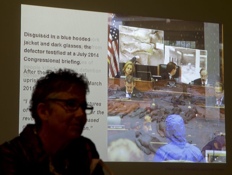 US Holocaust Memorial Museum visitor Marianne Kast, from Fresno, Calif., watches a slide show presentation of images of emaciated and mangled bodies from recent history in Syria in an exhibit entitled 