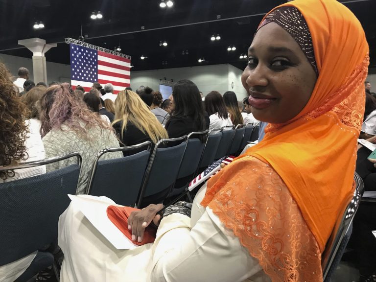 An immigrant from Uganda, who goes by Shubby, joins other immigrants taking the citizenship oath during naturalization ceremonies at a U.S. Citizenship and Immigration Services ceremony in Los Angeles on Sept. 20. (AP Photo/Damian Dovarganes)