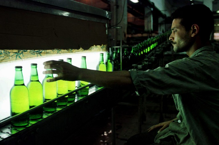 FILE - In this Saturday, July 26, 1997 file photo, an Egyptian worker inspects a bottle of Stella beer rolling down the line at a factory in Cairo, Egypt. Egypt's Civil Aviation Ministry is considering a ban on the sale of alcohol in airport duty-free stores after it received complaints that it goes against the country's Islamic principles, ministry officials and a senior lawmaker said Tuesday. (AP Photo/Enric Marti, File)