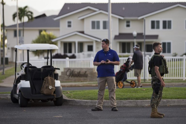 Secret Service and police work by a golf cart as a man with golf equipment walks by while President Barack Obama plays golf, Wednesday, Dec. 31, 2014, at Marine Corps Base Hawaii's Kaneohe Klipper Golf Course in Kaneohe Bay, Hawaii during the Obama family vacation. (AP Photo/Jacquelyn Martin)