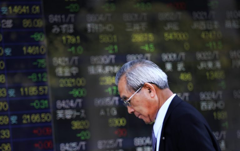 A man walks by an electronic stock board of a securities firm in Tokyo, Friday, Oct. 17, 2014. Asian stock markets mostly steadied Friday after a fall in U.S. unemployment applications and comments from a Federal Reserve official eased nerves about a stalling economic recovery. (AP Photo/Eugene Hoshiko)