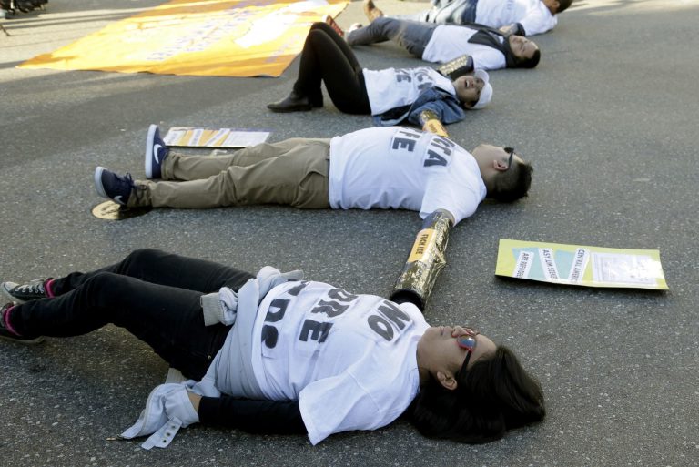 Immigration activists tied together by the arms participate in a sit-in protest against the U.S. Immigration and Customs Enforcement (ICE) raids and deportation of immigrants, on Tuesday, Jan. 26, 2016, near the downtown Los Angeles Federal Building. Organizers said in a news release they would be demanding a stop to deportation of Central American immigrant families and recognition that they are refugees seeking asylum. (AP Photo/Nick Ut)