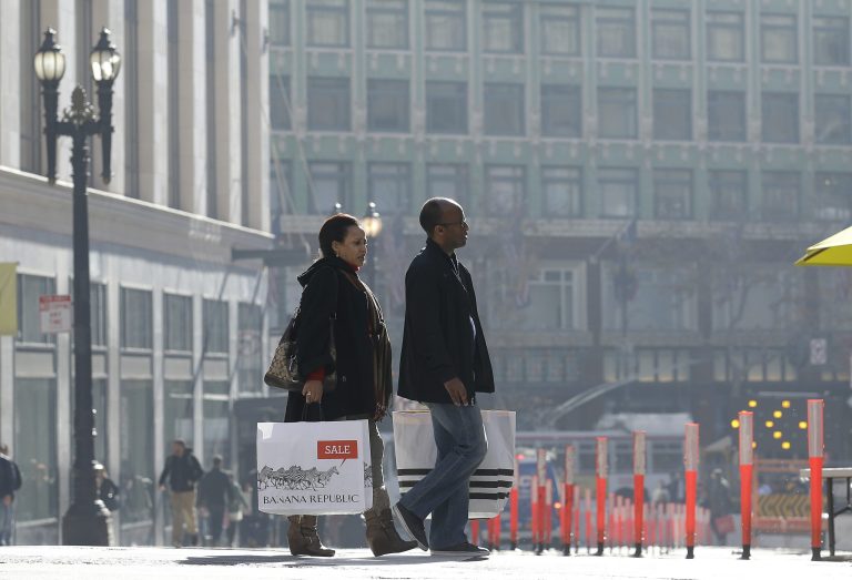 FILE - In this Tuesday, Dec. 24, 2013, file photo, a man and woman carry shopping bags as they cross the street in San Francisco. The Commerce Department reports how much consumers spent and earned in December. on Friday, Jan. 31, 2014. (AP Photo/Jeff Chiu)