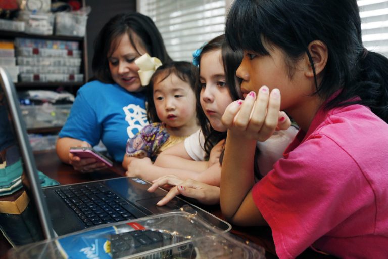 In this April 4, 2013 photograph, the Smith women, from left, mother Niki Smith, GiGi, 3, Macy Jade, 7 and Guan Ya, 14, use Google Translate on the family laptop to 