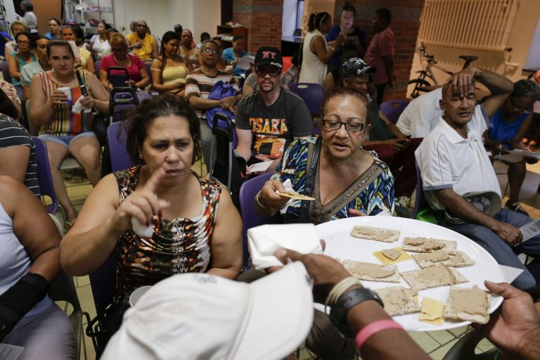 Food pantry customers are served samples of a donated pate of duck foie gras while waiting their turns to shop, Wednesday, July 2, 2014, in New York. About 170,000 pounds of delicacies left from the Summer Fancy Food Show in New York were donated and distributed to food pantries across the five boroughs..(AP Photo/Julie Jacobson)