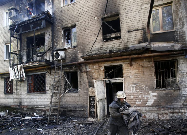 A firefighter carries an additional water hose at damaged apartment building after shelling in the town of Donetsk, eastern Ukraine, Wednesday, Sept. 17, 2014. Ukraine moved to resolve months of crisis Tuesday by strengthening ties to Europe and loosening some controls over the country's rebellious eastern regions where it has been fighting Russian-backed separatists. (AP Photo/Darko Vojinovic)