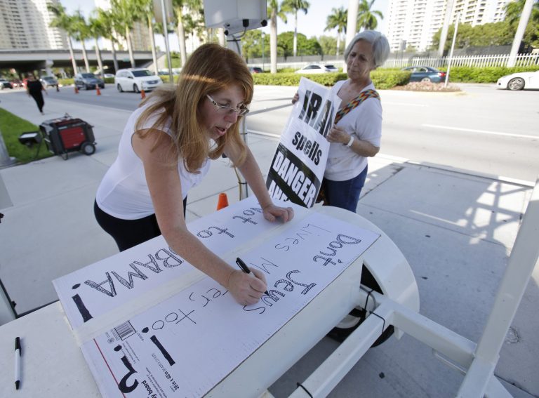 Caren Besner, center, of Boynton Beach, Fla., draws up a sign that says, 