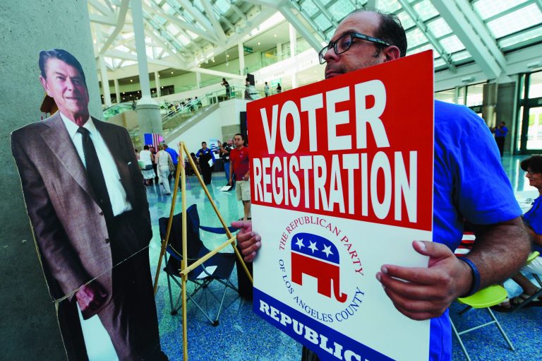 A Republican party volunteer standing next to a cardboard cut out of former President Ronald Reagan soliciate newly naturalized U.S. citizens to register to vote in voter registration booth sponsored by the Republican Party in Los Angeles.  (Photo by Kevork Djansezian/Getty Images)