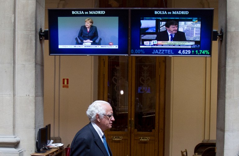   German Chancellor Angela Merkel is seen on a screen as a broker arrives at the stock exchange in Madrid, Thursday June 14, 2012. Spain's borrowing rates have hit a high not seen since the country joined the euro in 1999 after a credit ratings agency downgraded the country's ability to pay down its debt. The interest rate, or yield, on the country's benchmark 10 years bonds rose to a record 6.96 percent in early trading Thursday, close to the level which many analysts believe is unsustainable in the long term and at which countries such as Greece, Ireland and Portugal have sought an international bailout. (AP Photo/Paul White)  