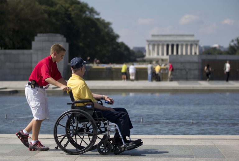   Korean War veteran Robert Olson, from Iowa, is pushed in his wheelchair by Zach Twedt, also from Iowa, around the National World War II Memorial in Washington, Tuesday, Oct. 1, 2013. Veterans who had traveled from across the country were allowed to visit the National World War II Memorial after it had been officially closed because of the partial government shutdown. After their visit, the National World War II Memorial was closed again. The Lincoln Memorial is seen in the distance. (AP Photo/Carolyn Kaster)  