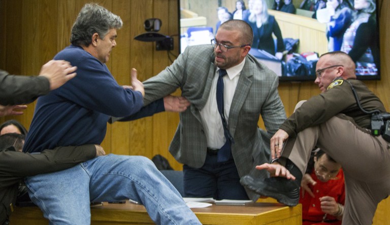 Randall Margraves, father of three victims of Larry Nassar , left, lunges at Nassar, bottom right, Friday in Eaton County Circuit Court in Charlotte, Mich. The incident came during the third and final sentencing hearing for Nassar on sexual abuse charges. (Cory Morse/The Grand Rapids Press via AP)