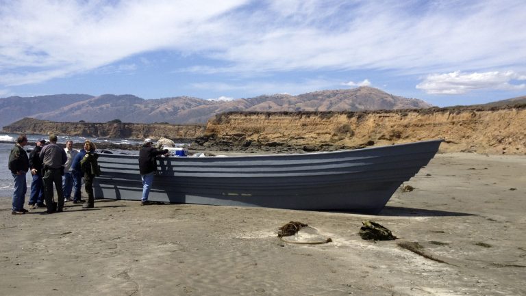 This image provided by the San Luis Obispo County Sheriff's Office shows officials at the site of a panga boat that was found Thursday June 26, 2014 near San Simeon, Calif. Authorities say the abandoned panga boat found on a Central Coast beach was possibly used to carry people and drugs. (AP Photo/ San Luis Obispo County Sheriff's Office)